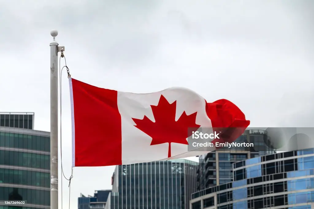 Canadian flag waving in front of a city skyline, symbolizing the vibrant urban environment and rich cultural diversity of Canada.